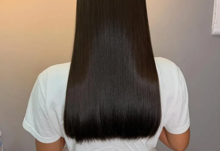 Cabelo escuro liso e alinhado até a metade das costas, visto de costas