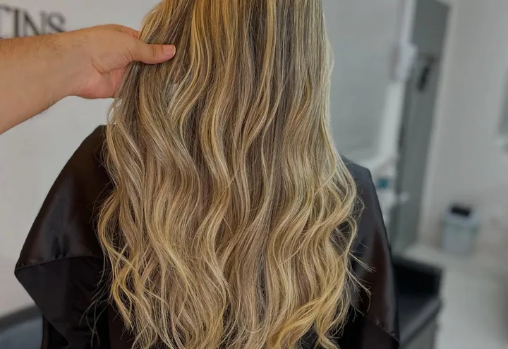 Cabelo loiro com mechas, finalizado em ondas soltas, visto de costas