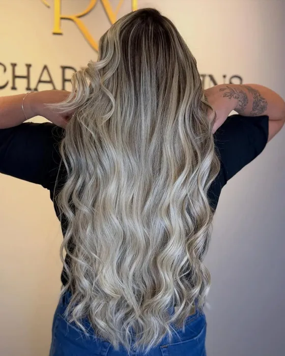 Cabelo loiro longo com mechas iluminadas em ondas, visto de costas