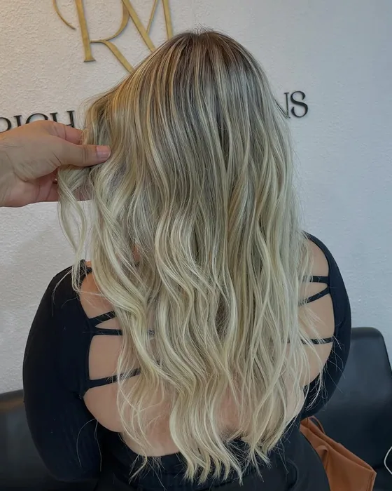 Cabelo loiro longo em ondas, com as pontas bem claras e a raiz esfumada, visto de costas