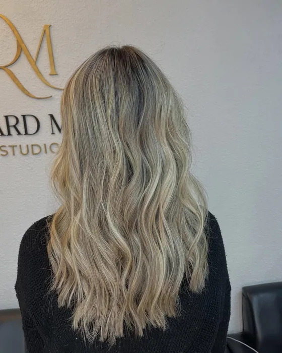Cabelo loiro com raiz esfumada em ondas soltas, visto de costas