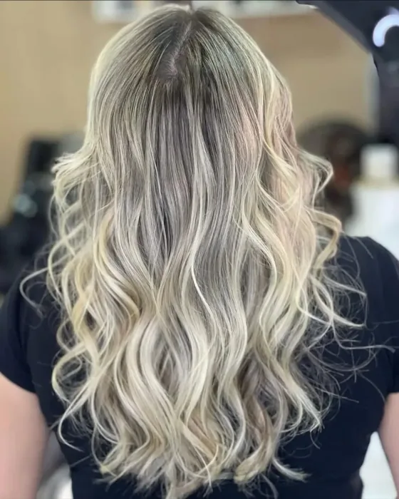 Cabelo loiro claro ondulado com raiz esfumada, visto de costas